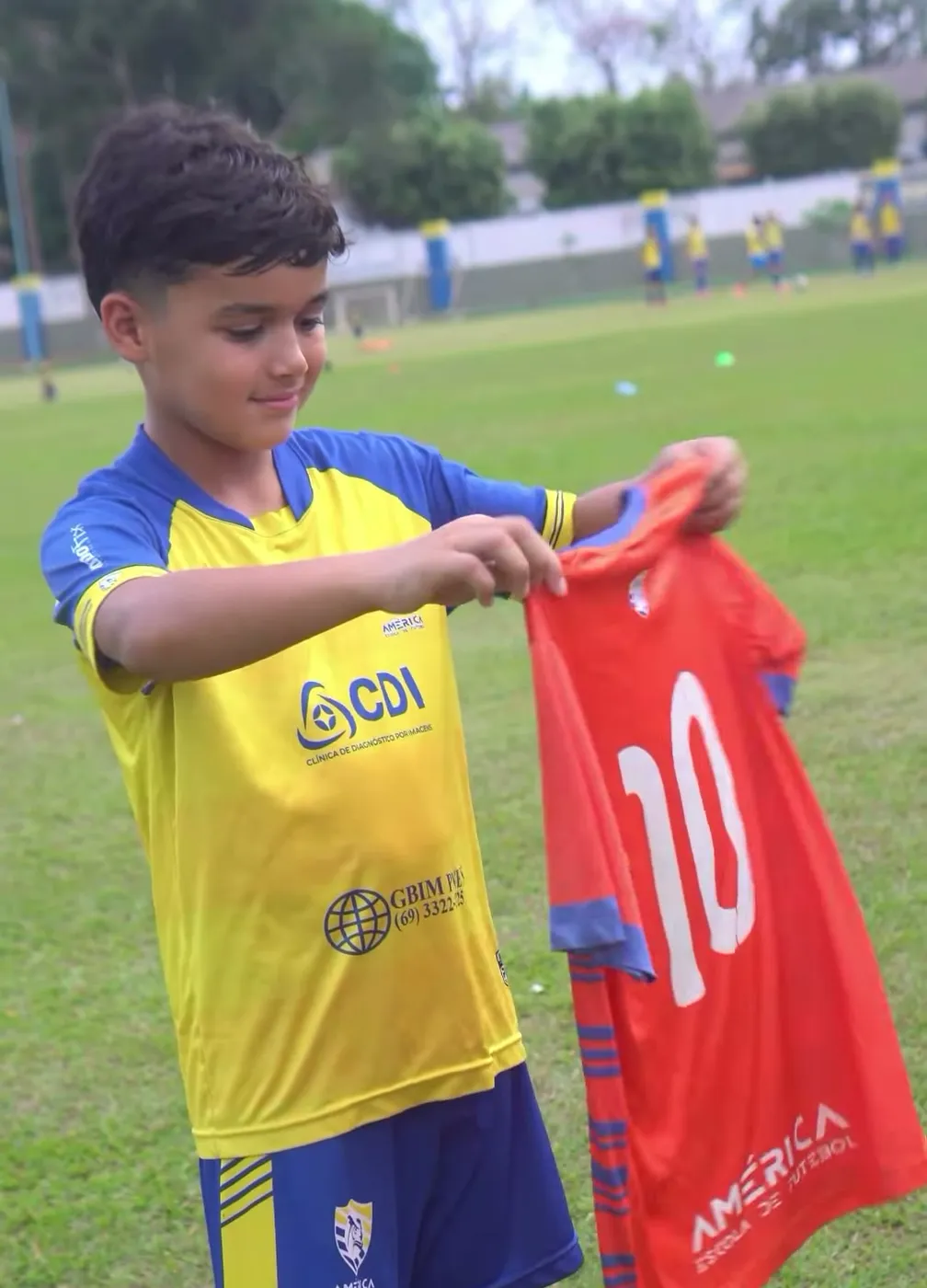 Aluno da América sorrindo ao segurar a camisa 10 da escola