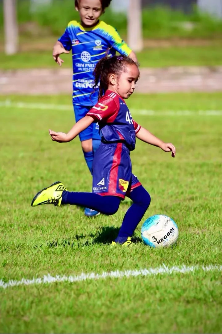 Menina da América conduzindo a bola em velocidade no gramado