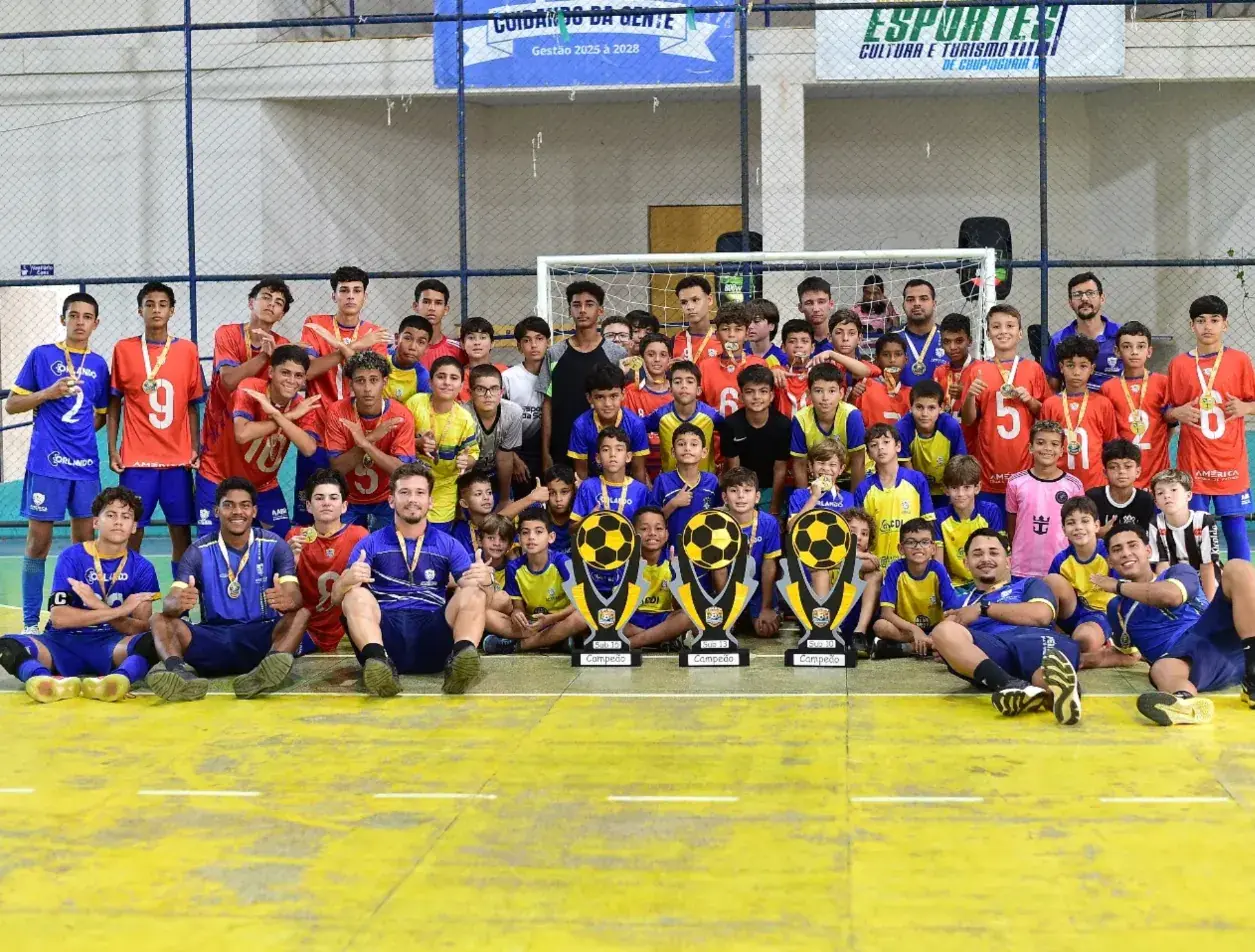 Atletas da América reunidos na quadra com três troféus de campeão